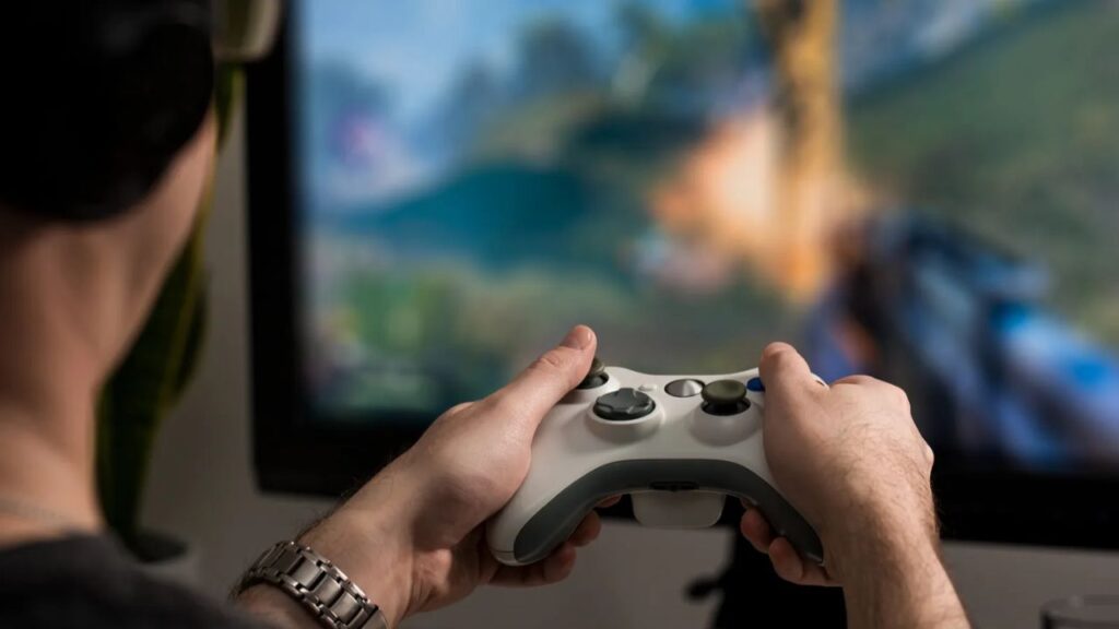 Man playing console game with joystick and headphones.