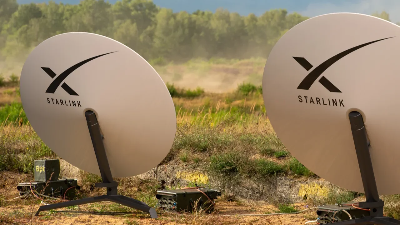Two Starlink satellite dishes set up in a rural field.