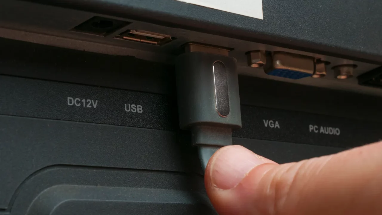 a man plug a hdmi cable in a TV.