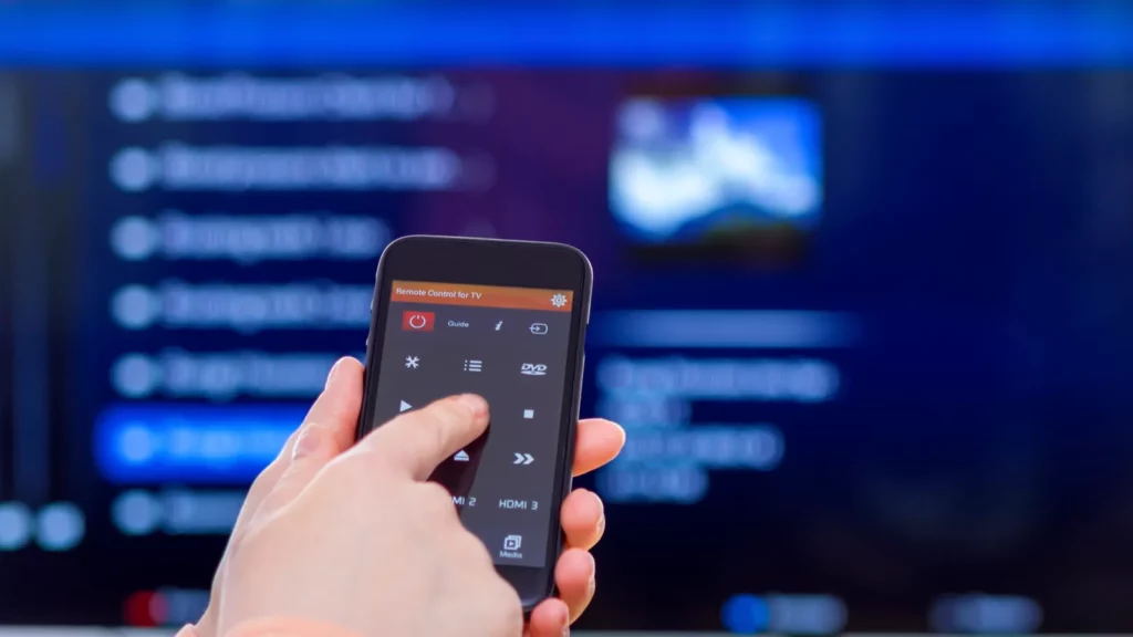 A woman hand holding smartphone trying to control TV with it.