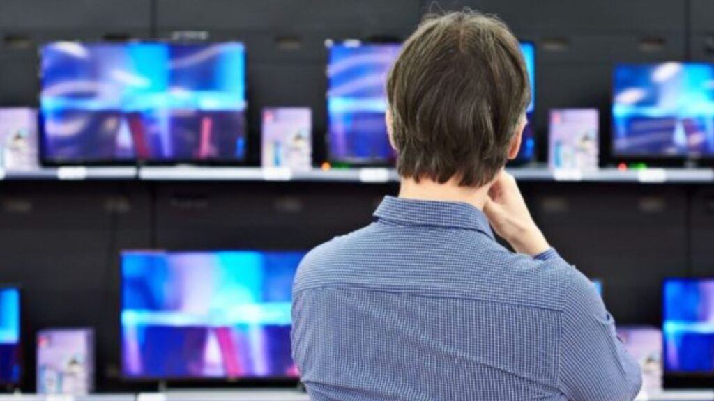 Vyras parduotuvėje žiūri televizorių.
