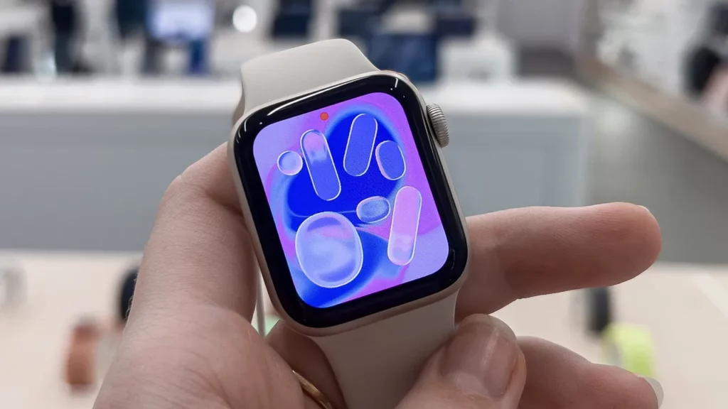 Hand holding a smartwatch with a colorful display.