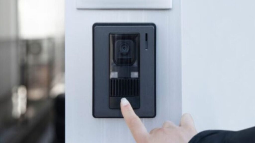 Pirštu paspaudžiamas vaizdo durų skambučio mygtukas.