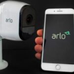 Arlo security camera beside smartphone.