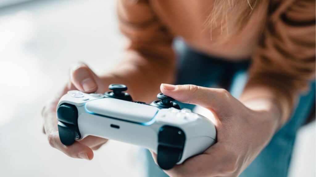 Person holding a PS5 DualSense controller.