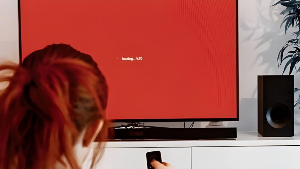 Person watching a TV displaying a red error screen.