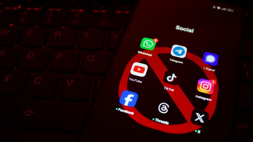 Išmaniojo telefono ekrane rodomos socialinės žiniasklaidos programos su raudonu draudimu.