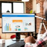 Person using a desktop monitor with charts.