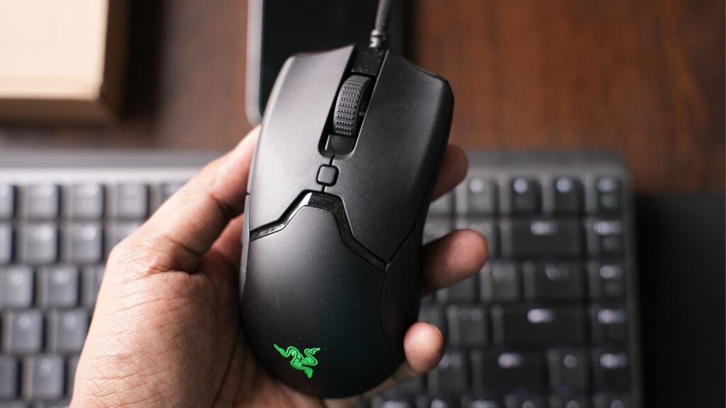 Vaikinas, laikantis mini žaidimų pelę razer viper.